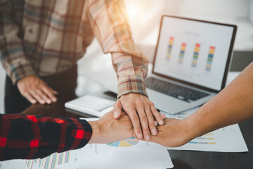  Businesspeople holding joined hands above desk with gadgets, Teamwork successful Meeting Workplace strategy with graph financial diagram top view.