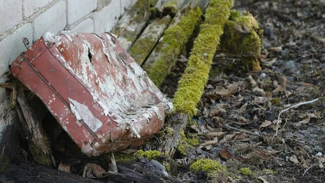 An abandoned red bag on the side of the house with the white paint on it in Estonia