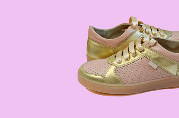 fashionable trendy leather golden children's or women's sneakers, stylish shoes in the autumn season isolated on colored background.