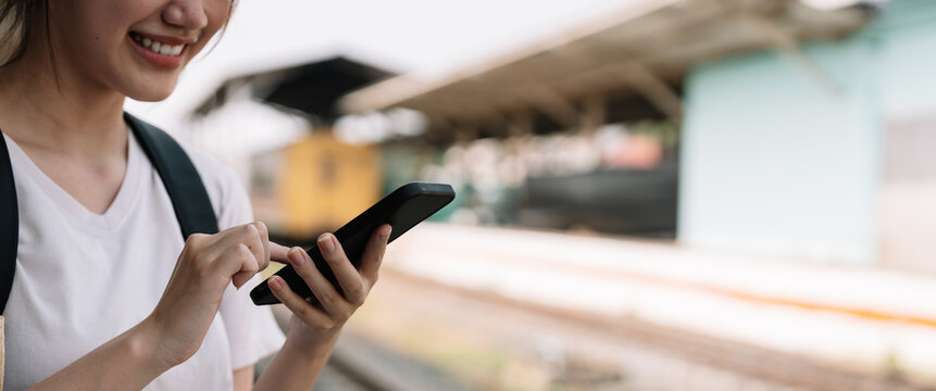 Close up hand of woman using smartphone at train station summer travel concept