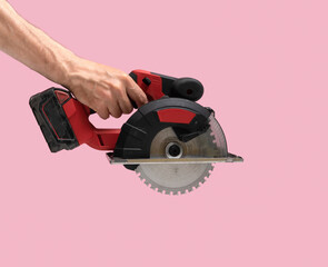 Man hand holds Brushless Cordless circular saw from left top corner on pink color background