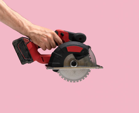 Man Hand Holds Brushless Cordless Circular Saw From Left Top Corner On Pink Color Background