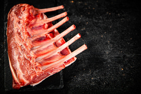 Raw rack of lamb on a stone board. On a black background. High quality photo