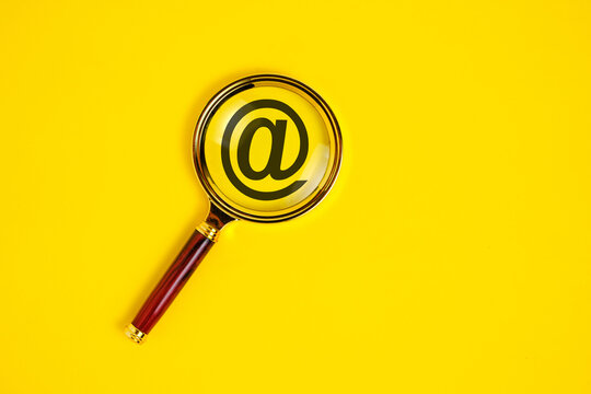 Dog sign is an email symbol under magnifying glass on yellow background.