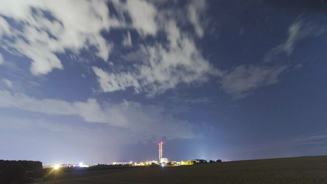 Silo tower behind fields at night with clouds and stars time lapse