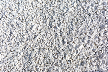 Crushed white stones form white gravel as a background, texture, pattern.