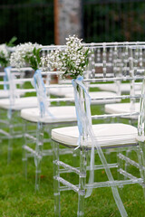 Flower-decorated chairs for guests at an outdoor wedding ceremony. Soft selective focus.