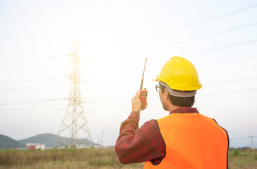 electrical engineer inspect the site near the high voltage tower.