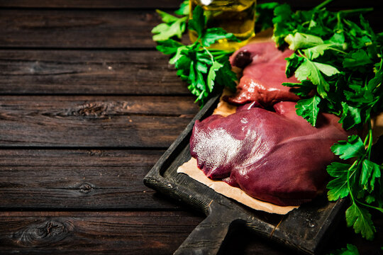 Raw liver on a cutting board on paper. On a wooden background. High quality photo