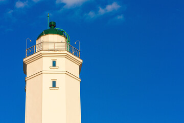 Fototapeta na wymiar A beautiful white lighthouse against a blue sky.