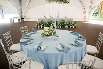 Floral table decoration for holidays and weddings. A set table for a celebration, event, party or wedding in an outdoor restaurant. Soft selective focus.