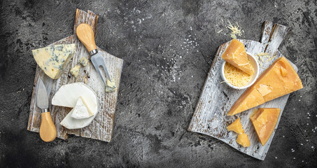 Piece of Parmesan cheese and assortment of different cheeses dor blu, camamber brie with knife on a dark background. Long banner format. top view