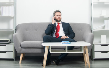businessman sitting in office and speaking on phone