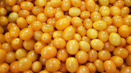 Lots of yellow tomatoes on the shelves in the supermarket.