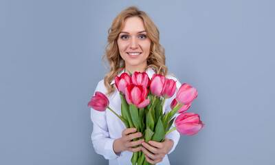 happy young woman hold spring tulip flowers on grey background