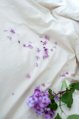Bed with beautiful white crumpled linenlinens in a white bedroom and Lilac flowers. Working office work remotely from home on bed. Distance learning online education and work.