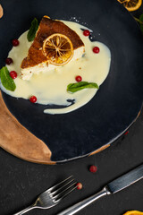 Classic cheesecake on a black background, dessert on a black background in a black plate