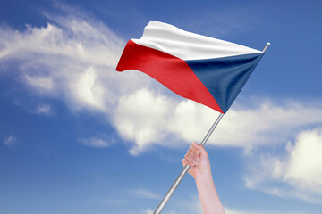 Female Hand is Waving Czech Republic Flag Against Blue Sky with Clouds