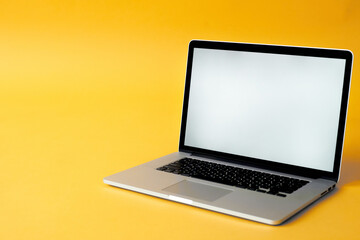 silver laptop on yellow background with white screen