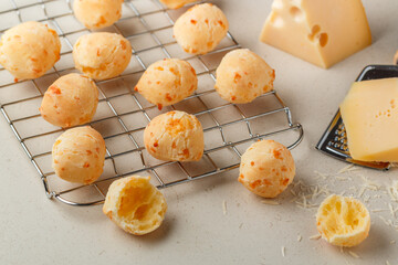 Freshly baked homemade cheese buns on a baking rack on a light background close-up. Brazilian cheese bread. A gourmet snack. Delicious pastries. Selective focus - 502939370