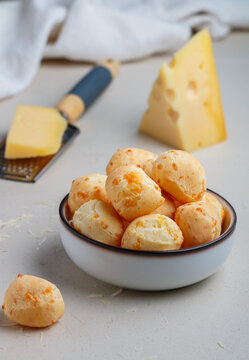 Brazilian cheese bread. Freshly baked homemade cheese buns in a white plate on a light background. A gourmet snack. Delicious pastries. Selective focus