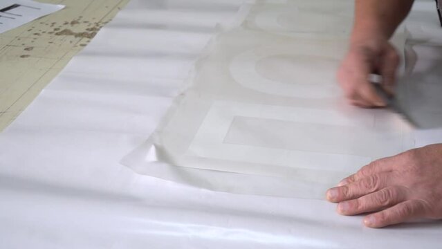 A man smooths out a transparent film on a sticker. advertising production. adhesive film for advertising