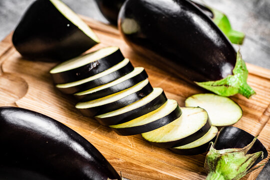Cut into pieces of ripe eggplant on a wooden cutting board. On a gray background. High quality photo