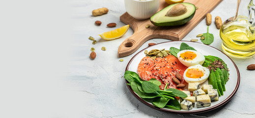 Keto diet food, salmon, avocado, cheese, egg, spinach and nuts. Ketogenic low carbs diet concept. Ingredients for healthy foods. Long banner format. top view