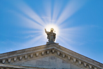 Obraz premium Statue of Jesus Christ surrounded by sun rays against clear blue sky