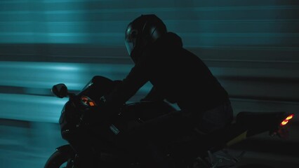 A man rides a sports motorcycle through the city at night
