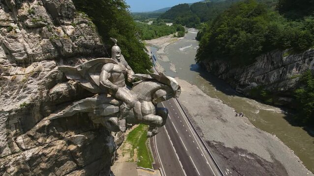Monument Uastirdzhi - St. George in the Alagir Gorge. The deity is the patron of warriors and men. Mountain river Ardon. The metal statue is embedded in the rock. North Ossetia Alania. Drone view