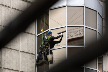 A worker washes window on the facade of a building