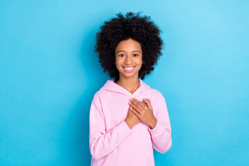 Portrait of attractive trendy cheerful bushy haired kind girl touching heart isolated over bright blue color background