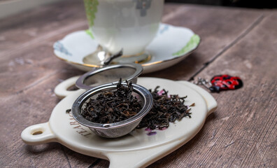 selected focus close up on stainless steel mesh tea strainer with dried black tea