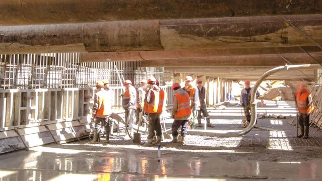 Workers pouring concrete in large huge ditch pit tunnel timelapse. Reinforcing structures from thick iron pipes of beams and structures at the construction site of the underground metro station line.
