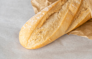 White loaf in paper, on a white background. Buy bread