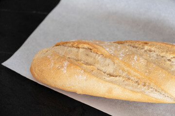White bread on parchment on a black table. Freshly baked bread