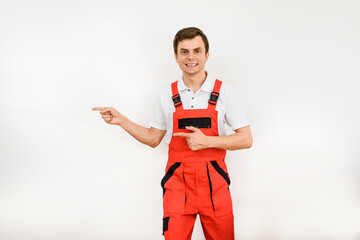 Young man contractor repairman builder in red overalls on white background.