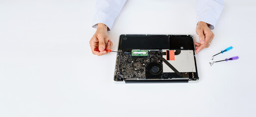 An IT technician in white robe is repairing a broken notebook laptop computer full of dust on white background.