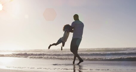 Animation of spots over happy african american father with daughter on sunny beach - Powered by Adobe