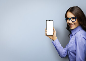 Portrait image of happy smiling young woman in eye glasses holding showing smartphone cell phone...
