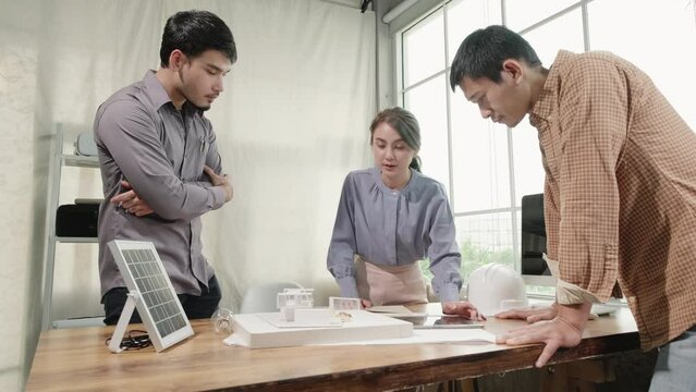 Architect Asian woman with teamwork present idea design modern house model together with renewable energy friendly is environmental in smart home concept.