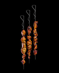 Three shish kebab skewers from the grill on black background