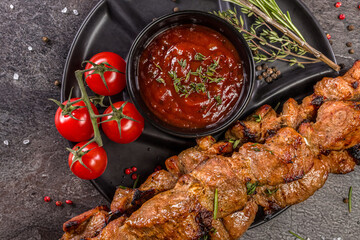 Shish kebab from the grill with fresh tomatoes and hot chili sauce with herbs