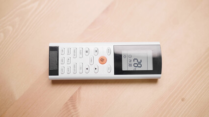 White and black AC remote controller on wooden table