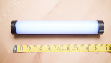 Person with measuring tape measure size of light tube on table