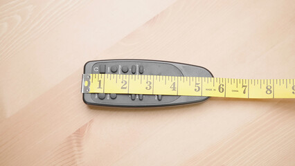 Measuring tape measure size of 6 inch remote controller on table