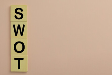 SWOT word on wooden cube over pink background with copyspace use for SWOT analysis Concept.