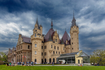 Obraz premium Zamek na tle ciemnego nieba otoczony zielenią.