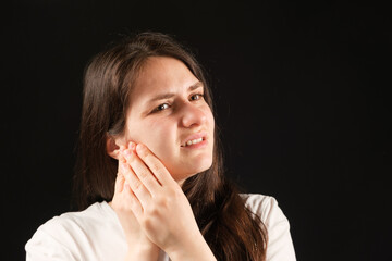 A woman holds her hands to a sore temporomandibular joint, dysfunction and pain, dislocated jaw,...